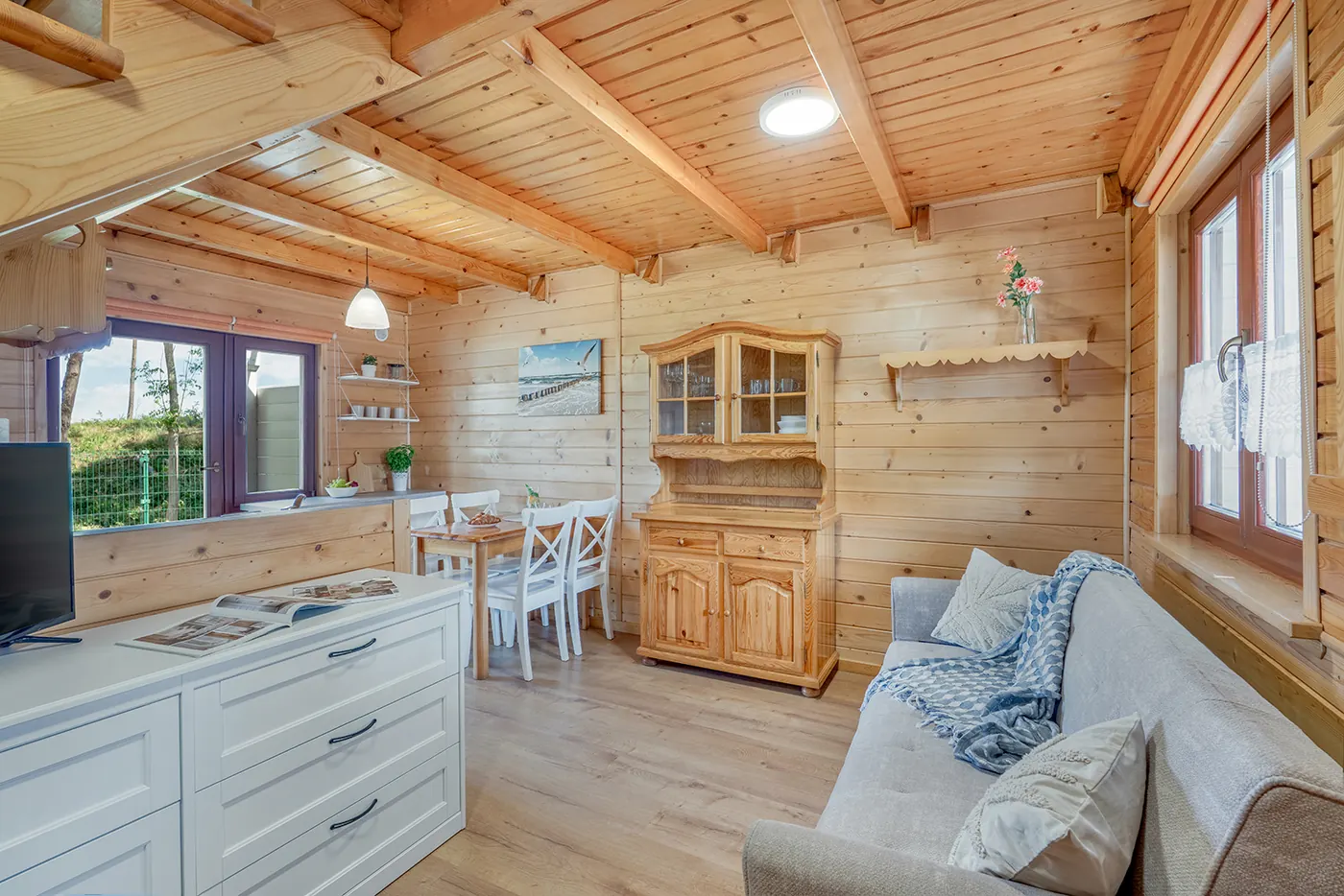 Salon z sofą, kredensem i jadalnią w drewnianym domku letniskowym w Sarbinowie