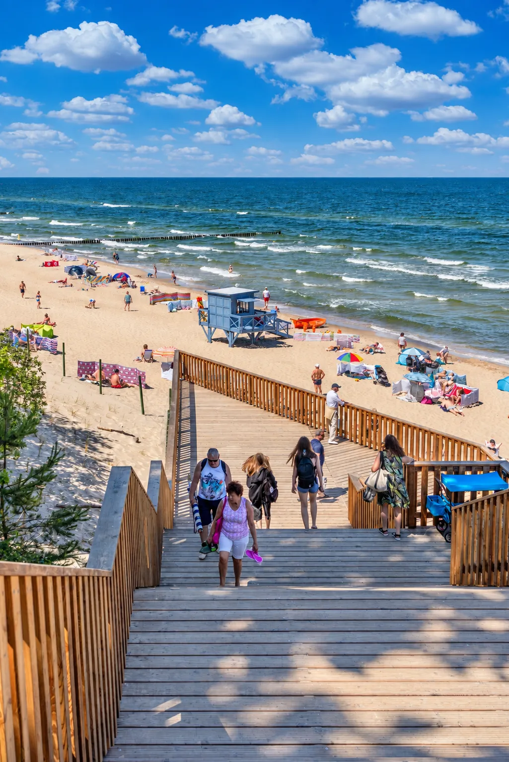 Zejście nr 2 na plażę w Rewalu z drewnianymi schodami i spacerowiczami