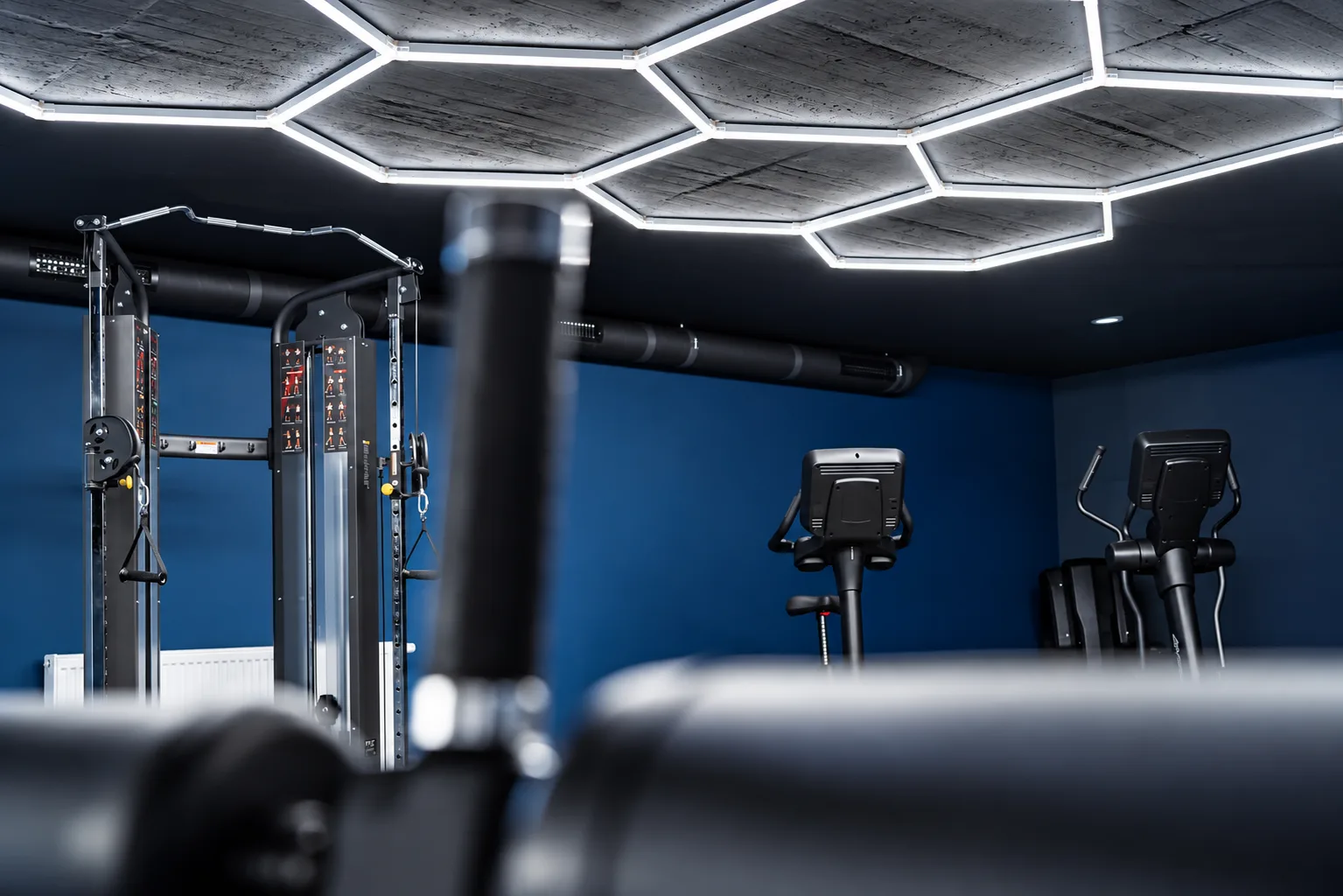 Atlas treningowy i orbitrek w granatowej sali fitness WhiteBlue, ujęcie z niskiej perspektywy
