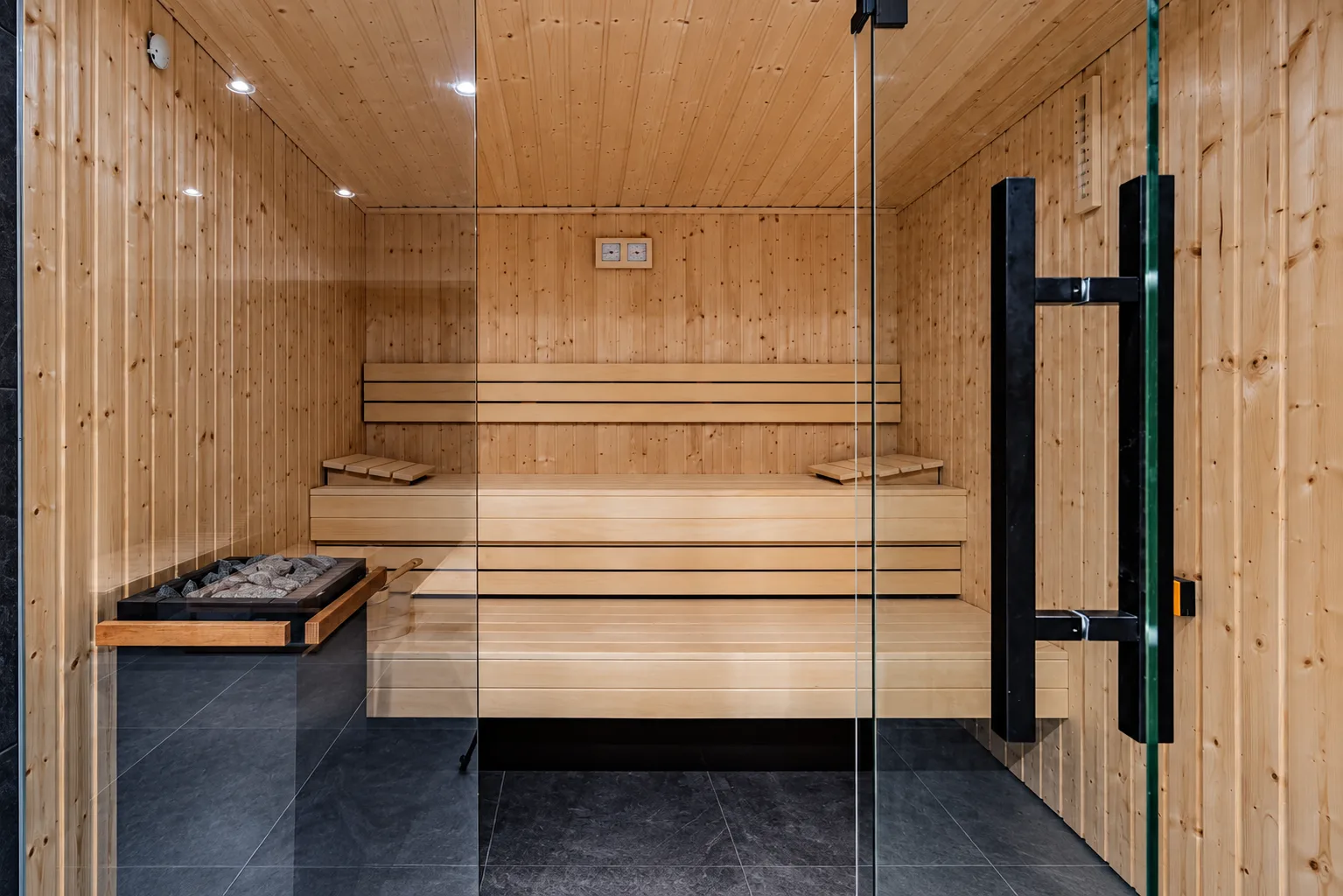 Drewniana sauna za szklanymi drzwiami w strefie wellness budynku WhiteBlue, Kołobrzeg