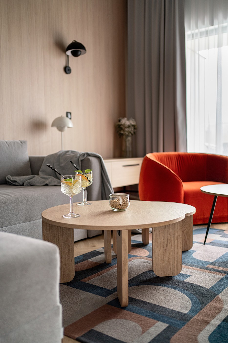 Strefa dzienna z jasną sofą i czerwonym fotelem, Apartamenty Rosa Style