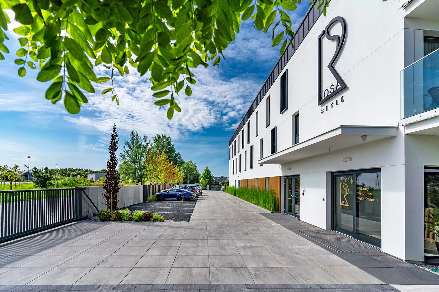 Front budynku z białą elewacją i logotypem, Apartamenty Rosa Style
