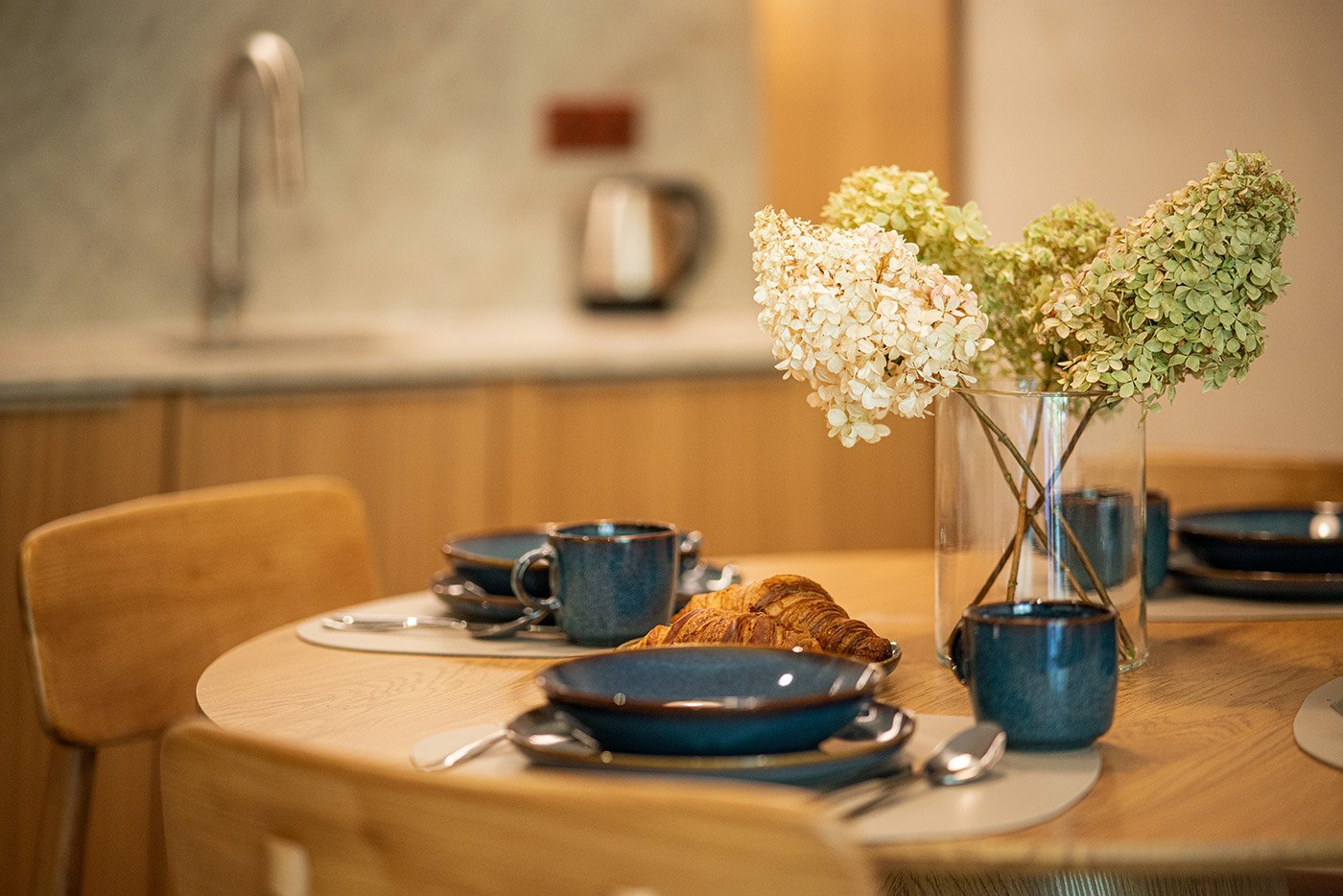 Nakryty drewniany stół z kwiatami i ceramicznymi naczyniami, Apartament Sea & Woods Star, Międzyzdroje