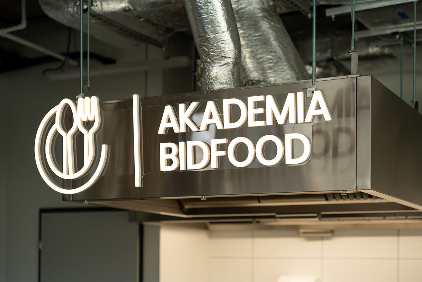 Podświetlany znak zawieszony pod technicznym sufitem, Akademia Bidfood