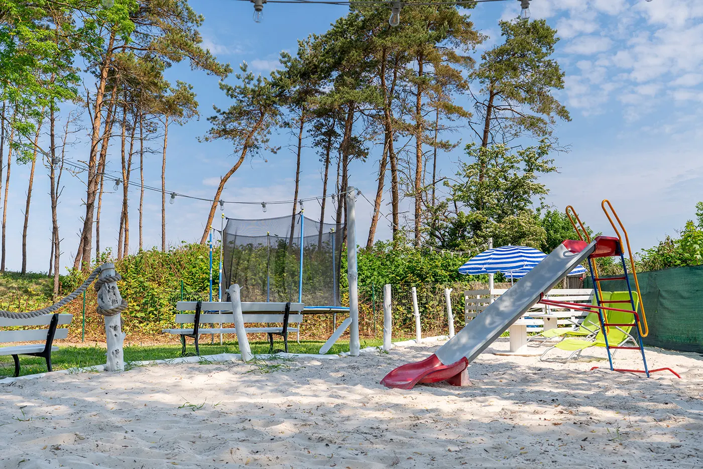 Otoczenie domków letniskowych w Sarbinowie – rząd białych budynków pośród sosen