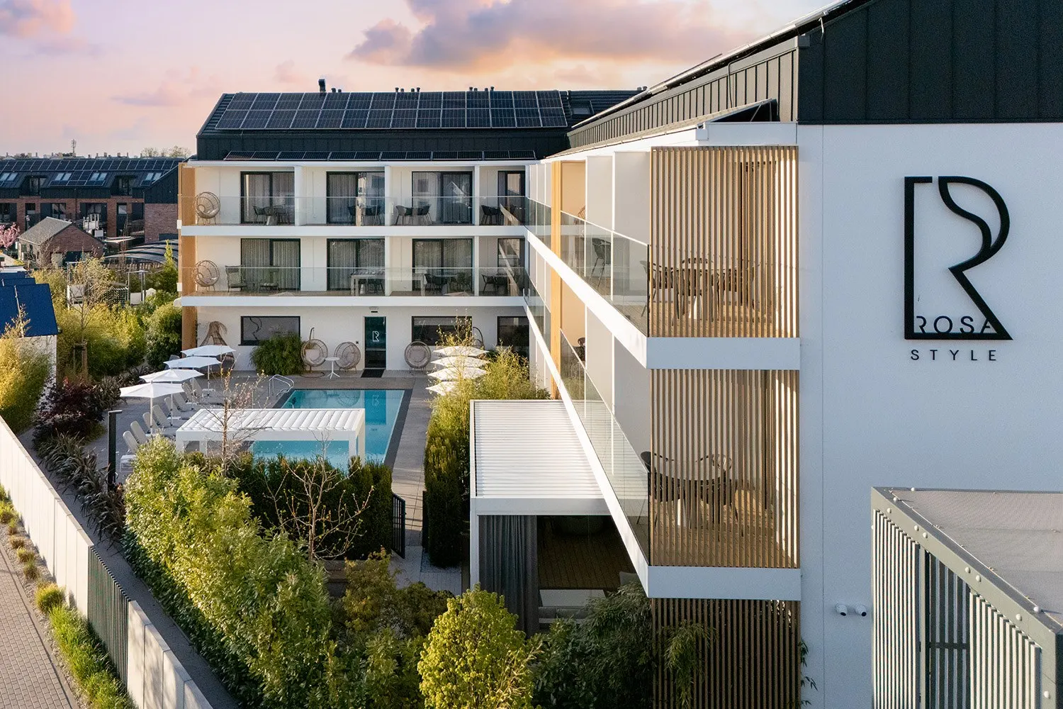 Elewacja apartamentów z logotypem i zielenią, Apartamenty Rosa Style